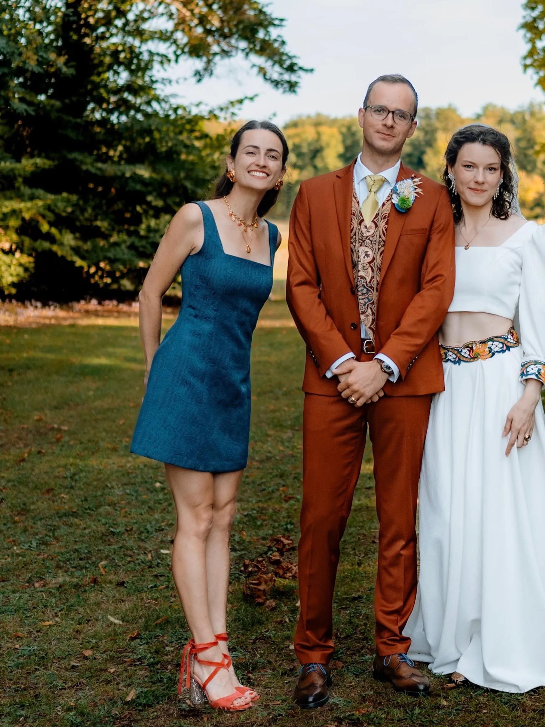 Agathe, à gauche, en robe bleue courte à col carré, pose avec les mariés sur une pelouse