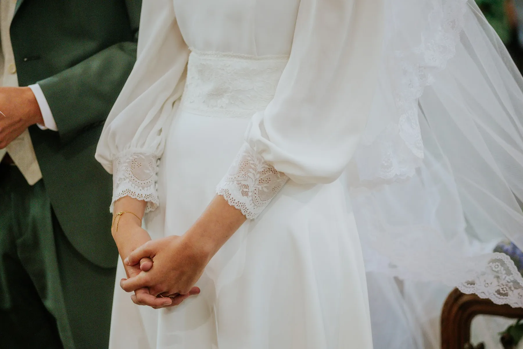 Détail de la robe de mariée d'Alice : manches longues à poignet en dentelle, ceinture en dentelle et voile bordé de dentelle