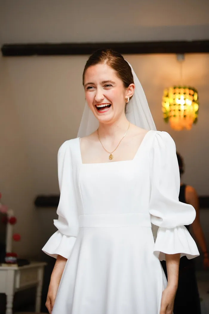 Amélie qui rit aux éclats, robe de mariée sur mesure à col carré et manches bouffantes à volants, voile court