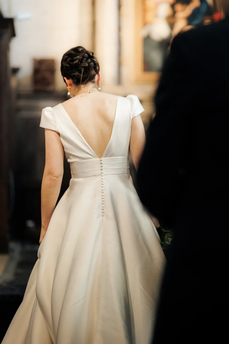 Dos de la robe de mariée d'Anne-Laure : décolleté V plongeant, manches courtes bouffantes, ceinture drapée et boutons couverts