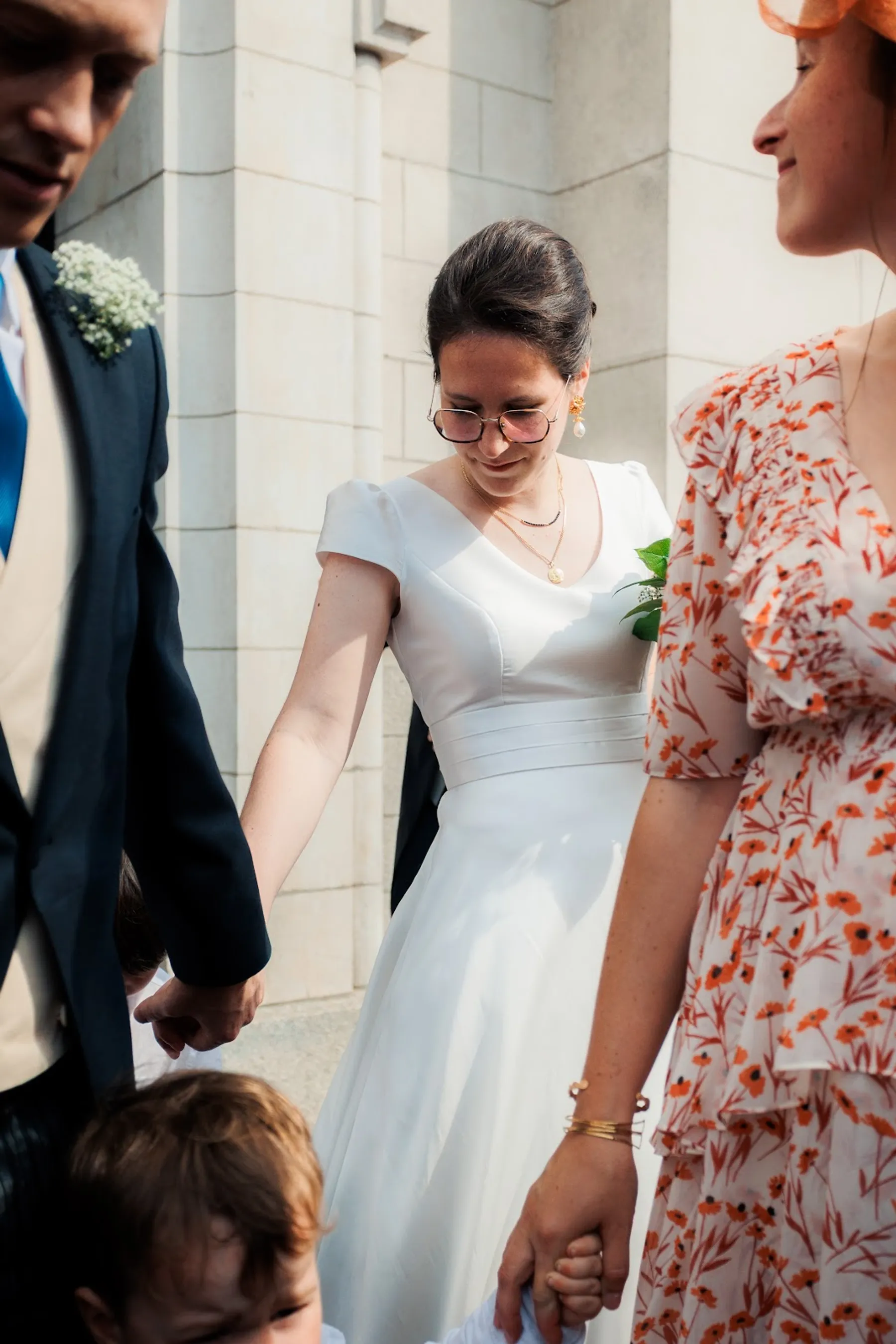 Anne-Laure en robe de mariée à col V, manches courtes et ceinture plissée, à la sortie de la cérémonie