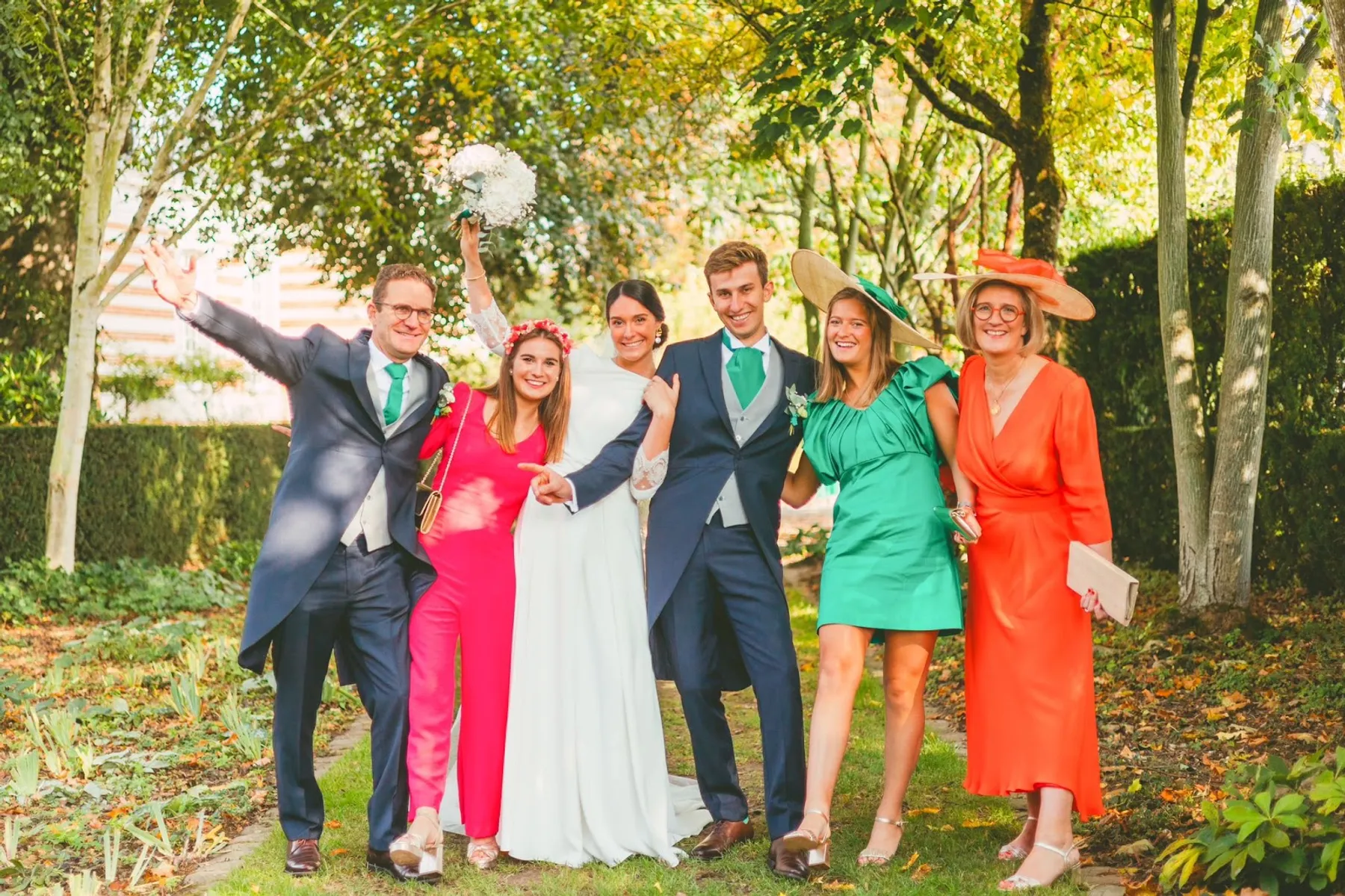 Invités posant avec les mariés dans un parc en automne ; Blanche porte la robe verte à épaules volantées et un chapeau