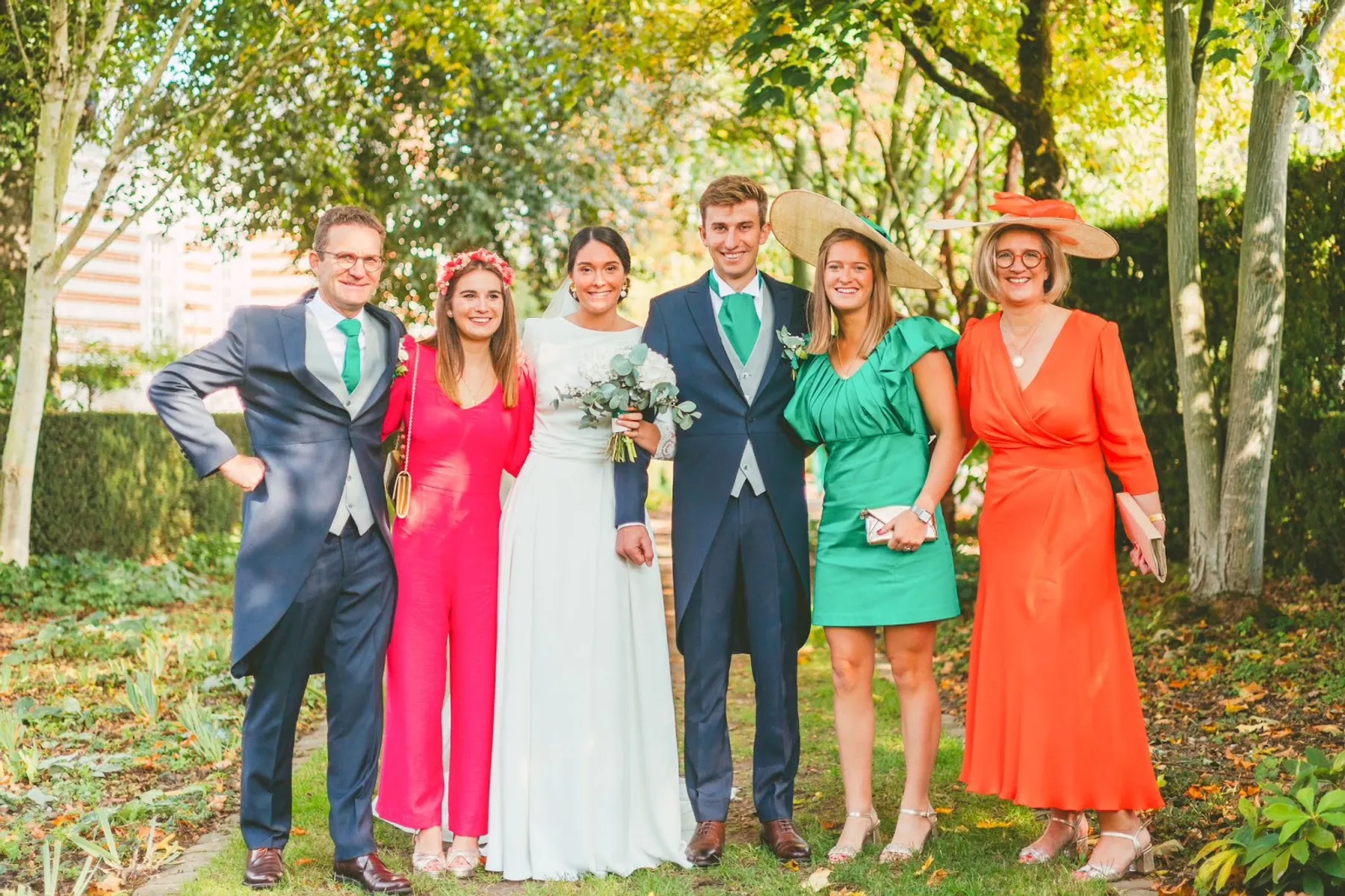 Jeanne en combinaison fuchsia, posant avec les mariés et d'autres invités dans un parc