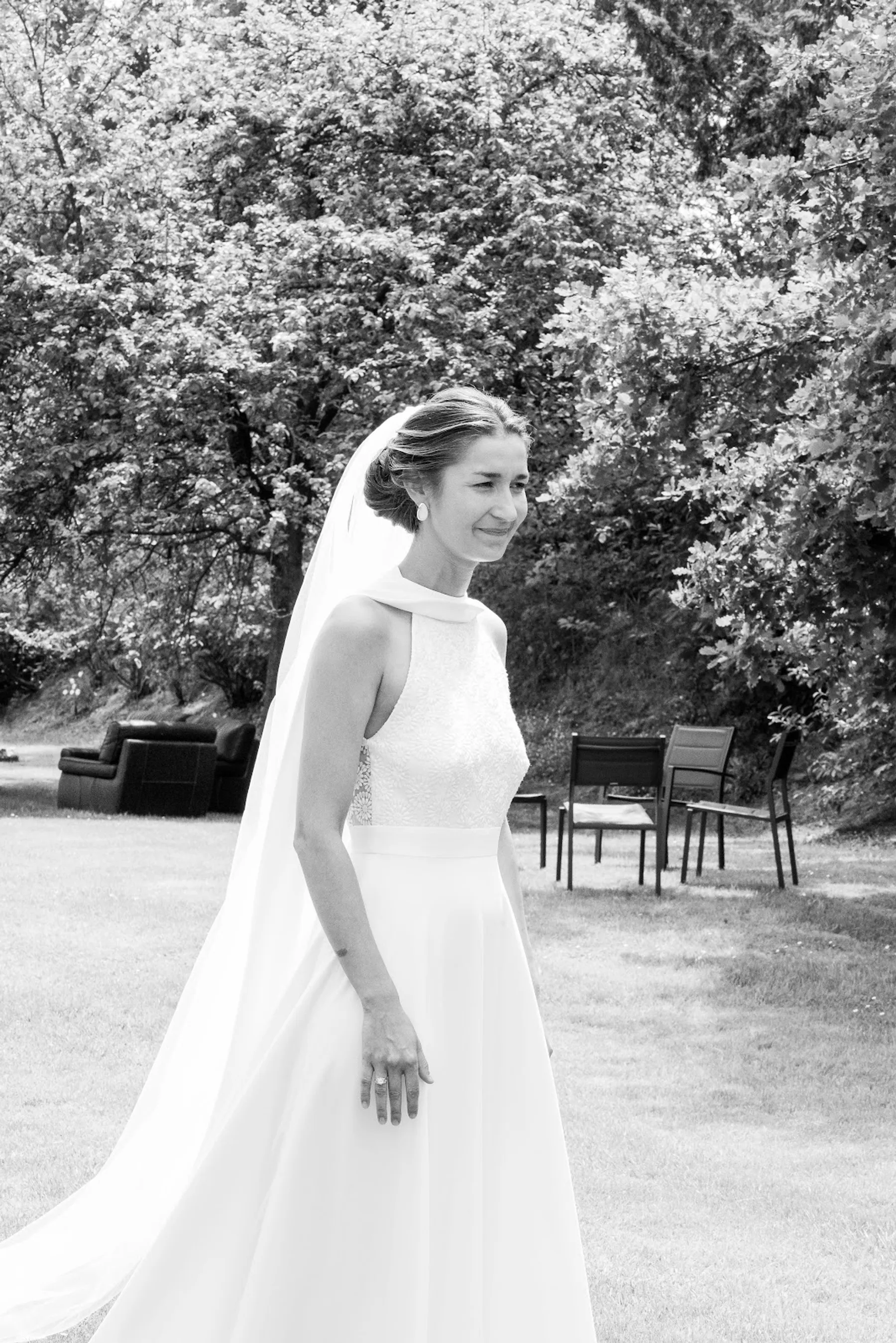 Lucie dans un jardin, robe de mariée à col montant et jupe évasée, voile long, photo en noir et blanc